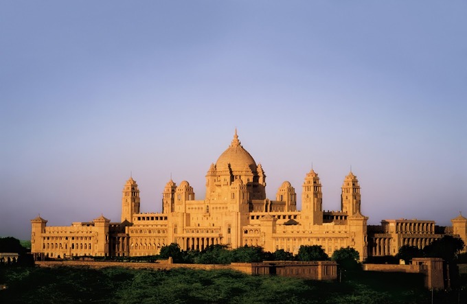 A large, symmetrical palace with multiple domes and towers under a clear blue sky stands as one of the best destination wedding resorts in India.